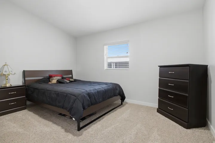 Neutral wall paint, light-colored carpeting, and a window with horizontal blinds