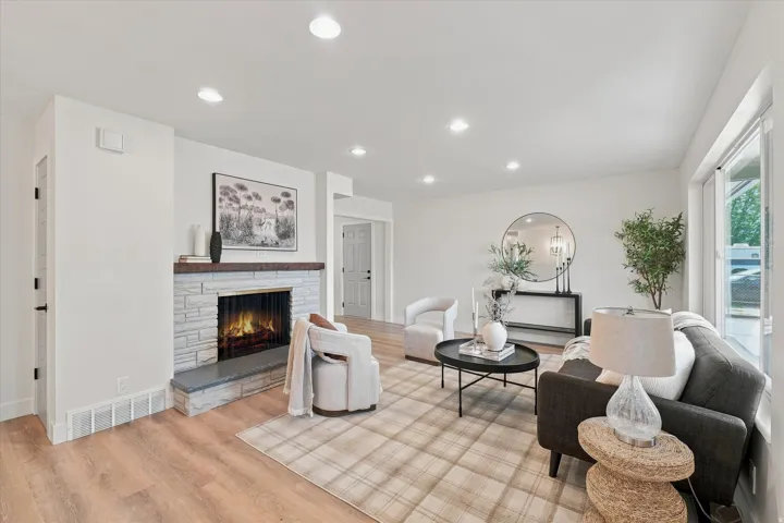 Living space featuring wood-finish flooring, recessed lighting, and a fireplace with a stone surround and wood mantel