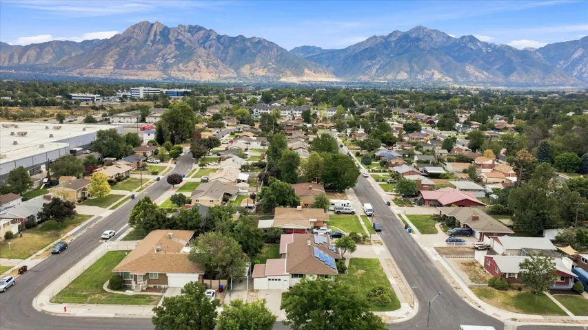 Mountain backdrop, residential neighborhood, paved streets, established landscaping, blue sky