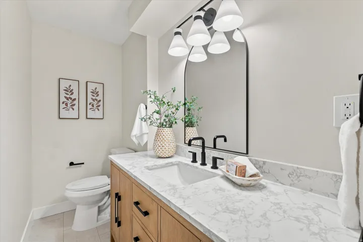 Wood-finish vanity with black hardware, white rectangular undermount sink, and a white countertop
