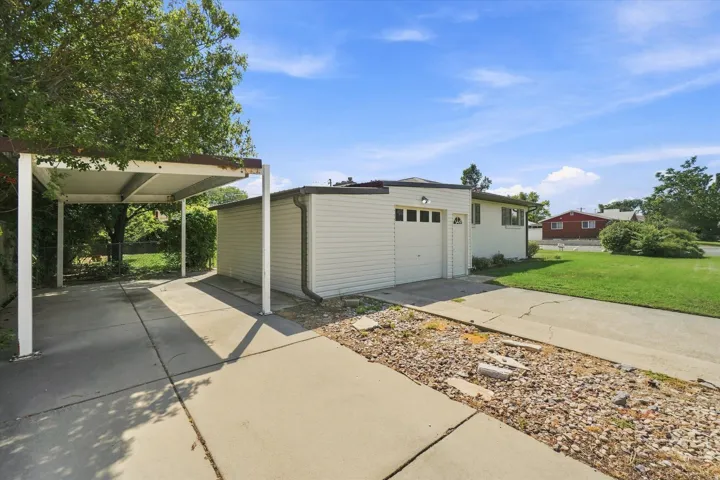 Attached carport for ADU with concrete driveway, single-car garage, and a manicured lawn
