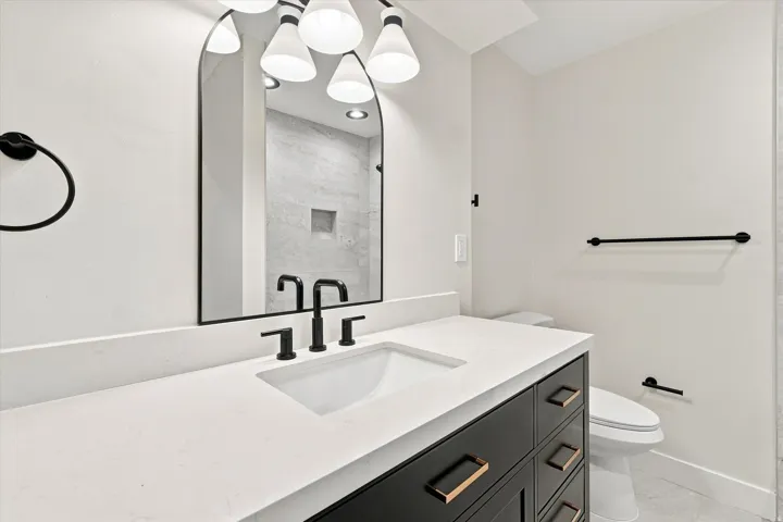 Integrated vanity featuring a white rectangular sink, matte black faucet, and white countertop