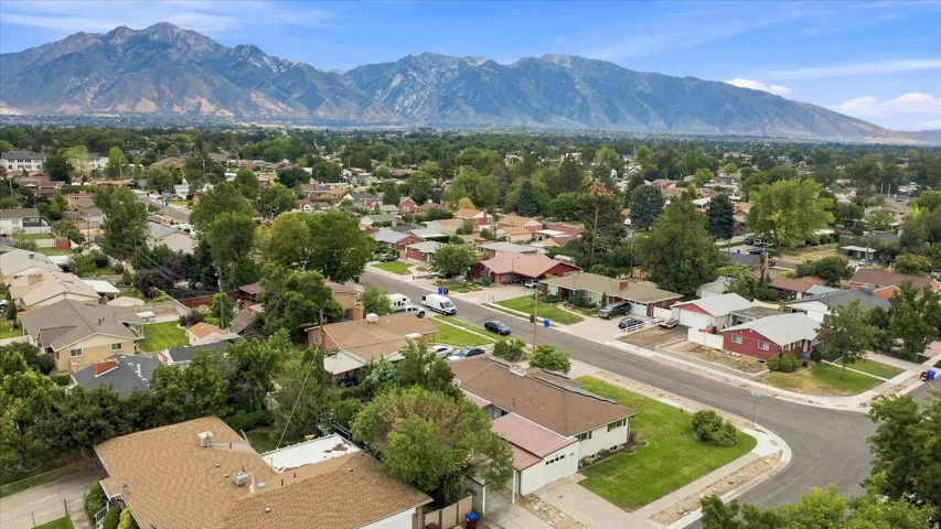 Residential neighborhood with mature trees, paved streets, and mountain backdrop