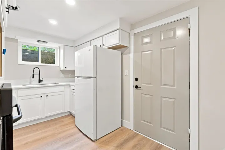 ADU with White cabinetry with black hardware, wood-finish flooring, recessed lighting, white countertop, and a black gooseneck faucet