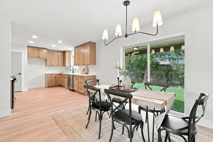 Wood-finish flooring throughout, light wood cabinetry, white countertops, and a sliding glass door leading to the exterior