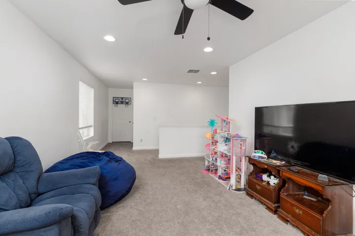 Recessed lighting, ceiling fan, white walls, carpeted flooring, and a window with blinds