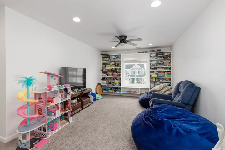 Carpeted room featuring built-in shelving, a ceiling fan with integrated lighting, recessed lighting, and a window with blinds