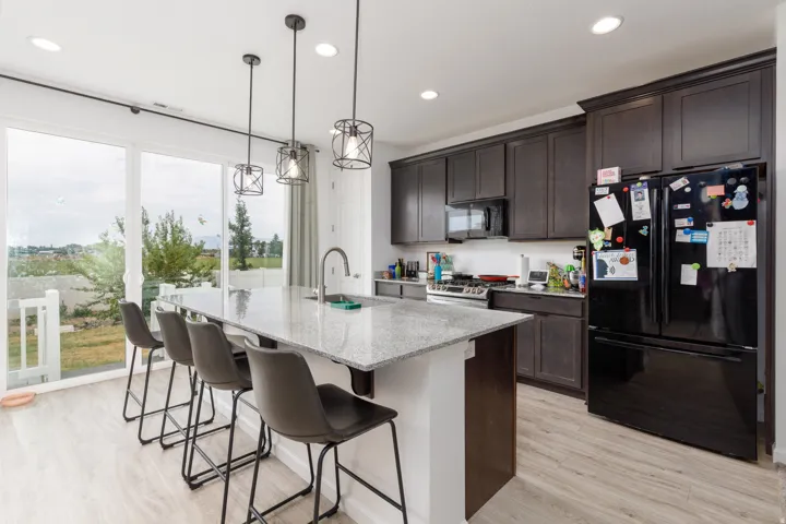 Kitchen featuring wood-finish flooring, dark wood cabinetry, a center island with a light-toned countertop, and recessed lighting