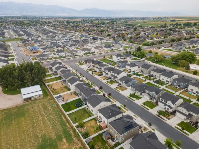 Residential development featuring multiple single-family homes, paved streets, and mountainous backdrop