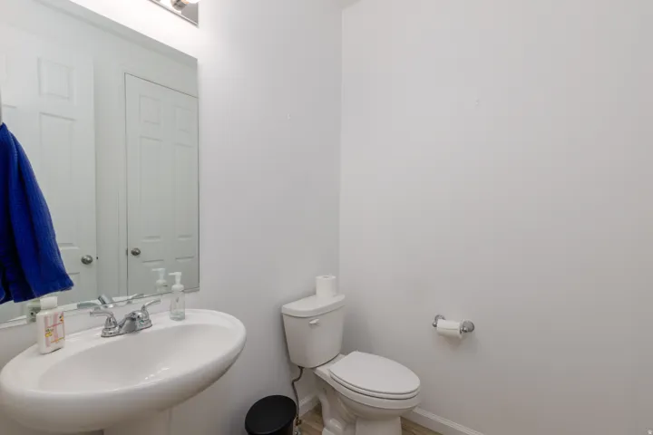 Pedestal sink with chrome-finish faucet, toilet, and light-toned flooring