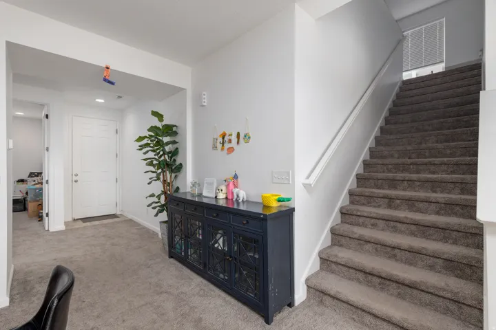 Carpeted staircase with white handrail, recessed lighting, and white interior doors