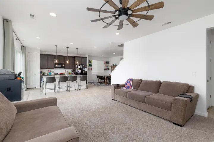 Open-concept living space featuring a ceiling fan, recessed lighting, and mixed flooring with light-toned wood-finish and carpet