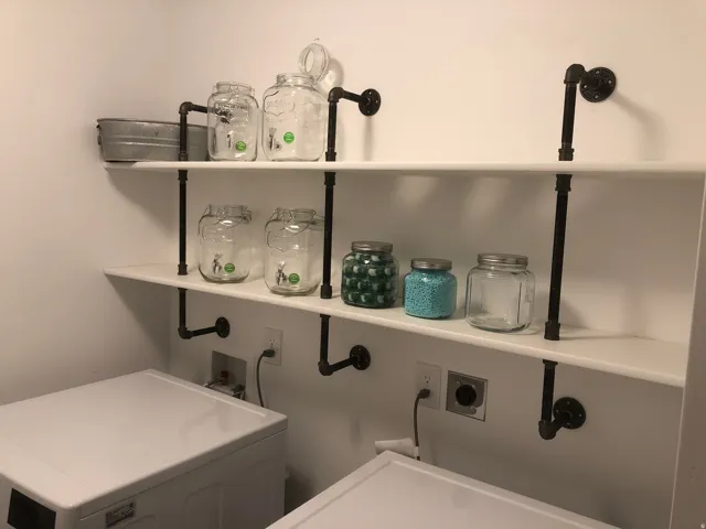White wall-mounted shelving with pipe-style brackets
