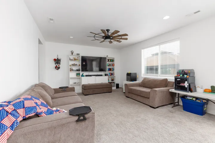 Spacious recreation room featuring neutral carpeting, recessed lighting, and a ceiling fan
