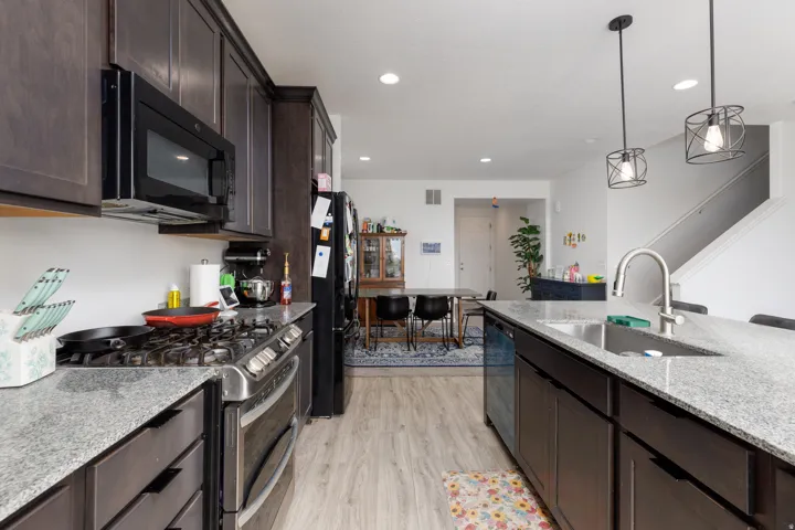 Kitchen featuring wood-finish flooring, dark wood cabinetry, stainless steel appliances, and light-colored countertops