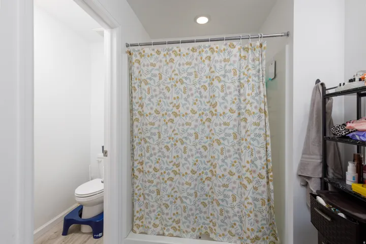 Recessed ceiling lighting, full shower, and wood-finish flooring