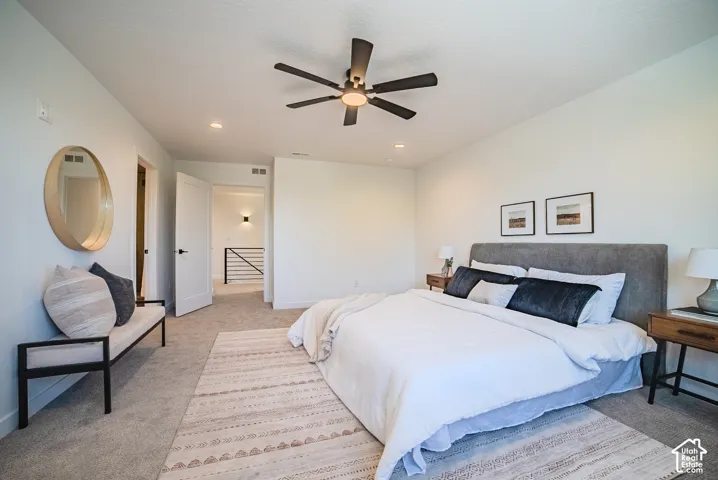 Recessed lighting, ceiling fan, white paneled doors, carpeted flooring, and modern iron railing