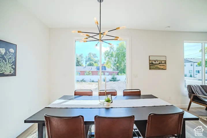 Bright dining space featuring a contemporary linear chandelier, large glass sliding door, and white walls
