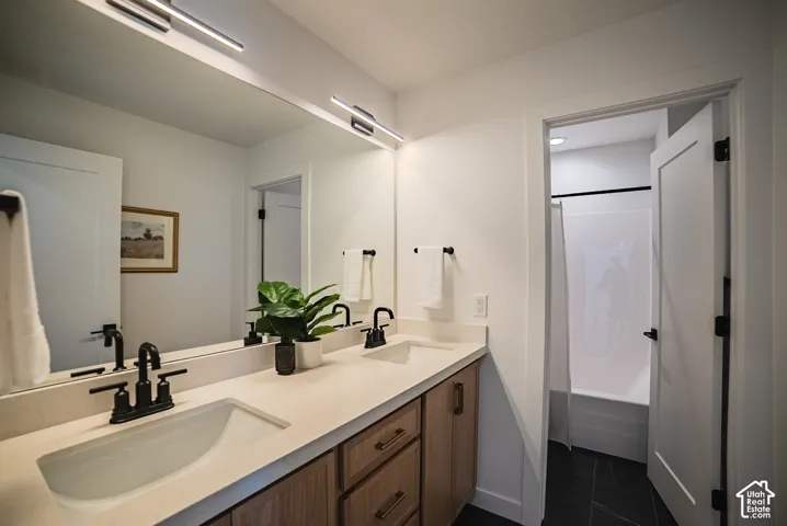 Dual vanity with integrated sinks and black fixtures, wood-finish cabinetry, light-toned countertop, and modern linear lighting fixtures