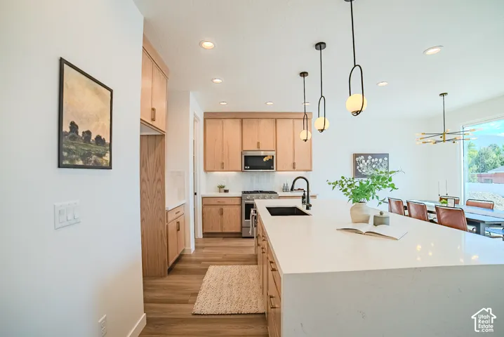 Light wood-finish cabinetry, white stone countertops, wood-finish flooring, and recessed lighting
