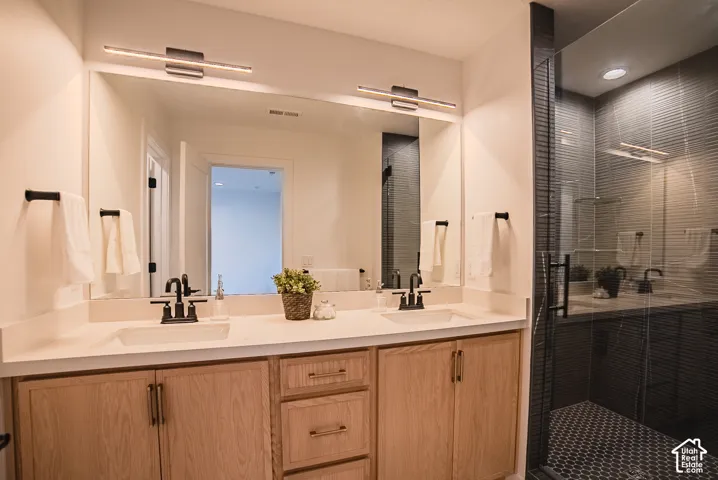 Dual vanity with integrated sinks, light wood-finish cabinetry, and black fixtures