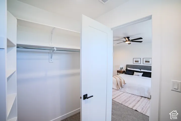 Built-in closet shelving with hanging rod, and a bedroom featuring a dark-toned ceiling fan