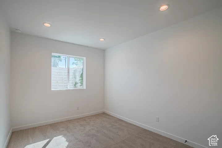 Recessed ceiling lighting, white walls, and light-toned carpeting