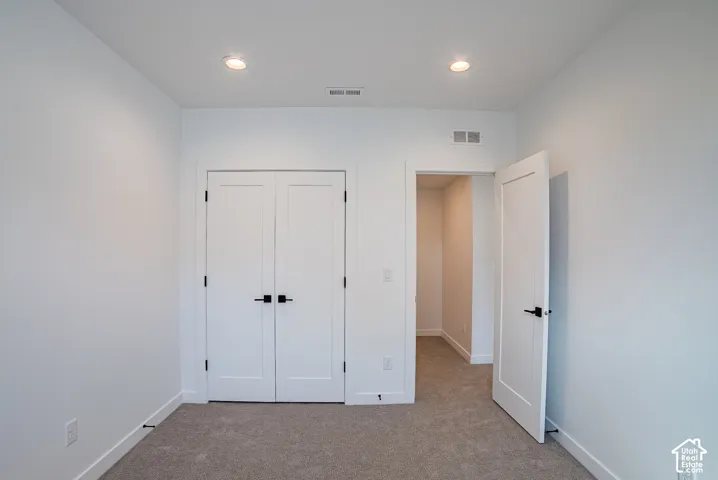 White interior walls with recessed lighting, light gray carpet, and white paneled doors with black hardware