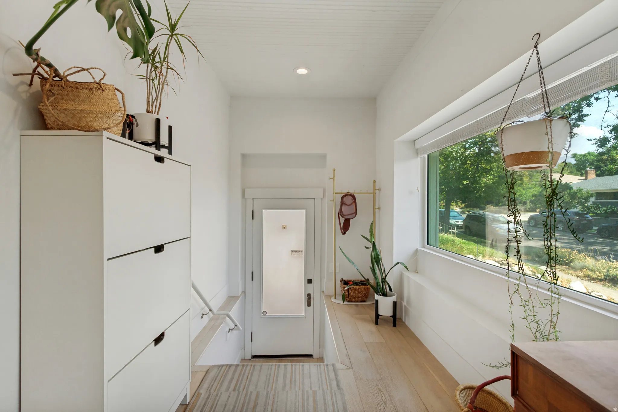 Recessed lighting, wood-finish flooring, full-light entry door, and a horizontal fixed-pane window