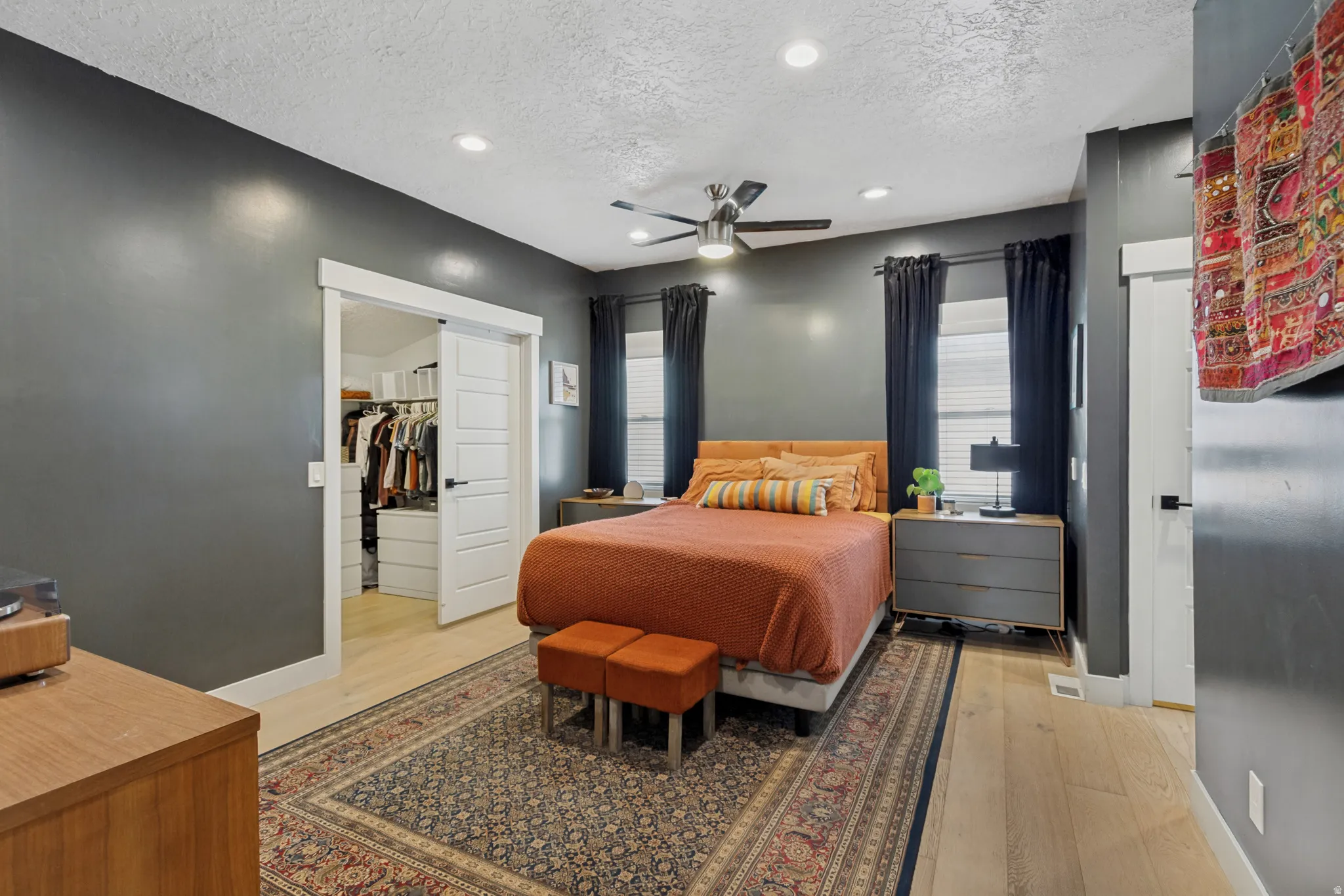 Recessed lighting, ceiling fan, sliding barn door, wood-finish flooring, and window blinds