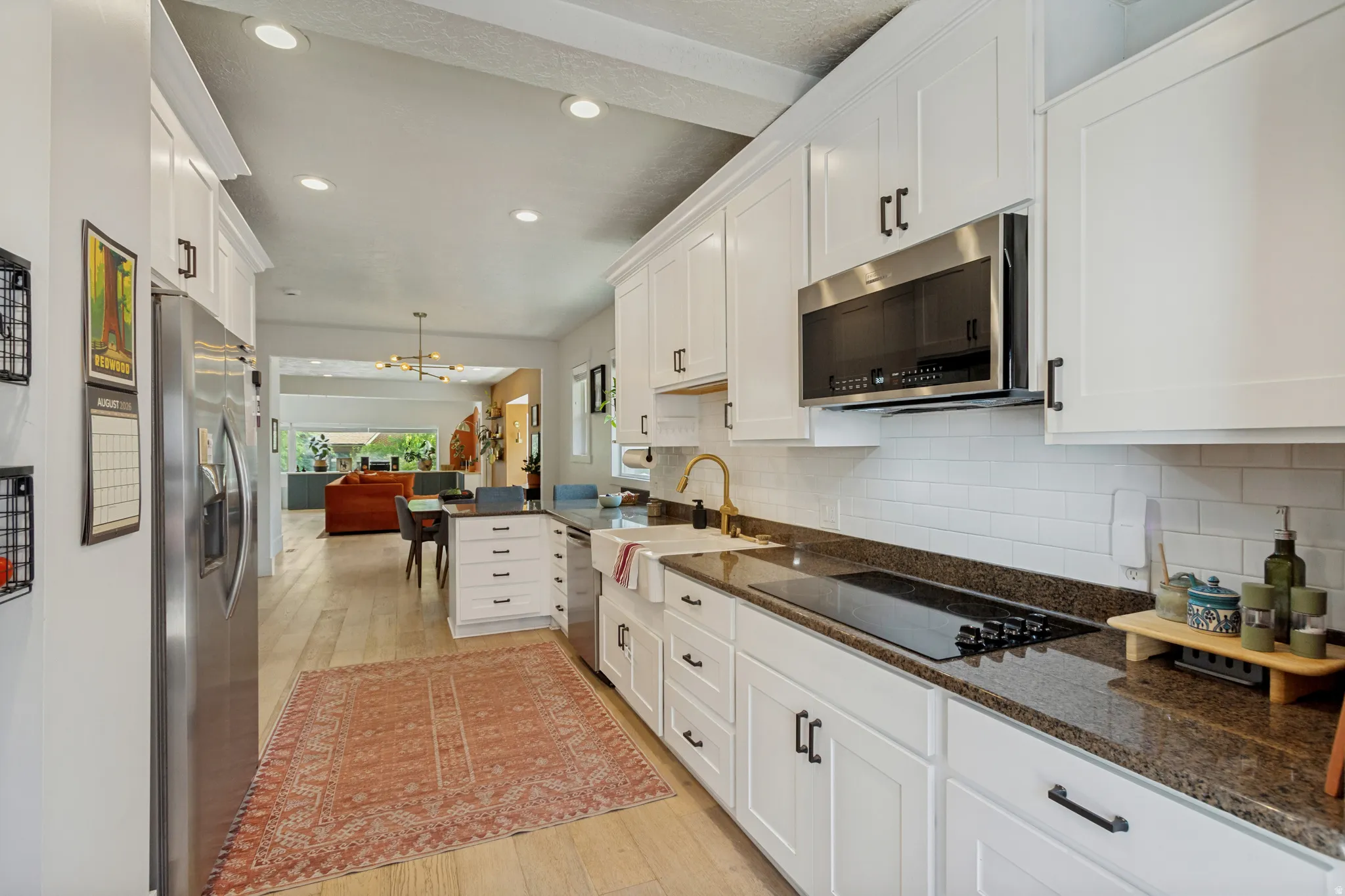 Kitchen featuring white shaker cabinetry, stainless steel appliances, dark stone countertops, and a white subway tile backsplash