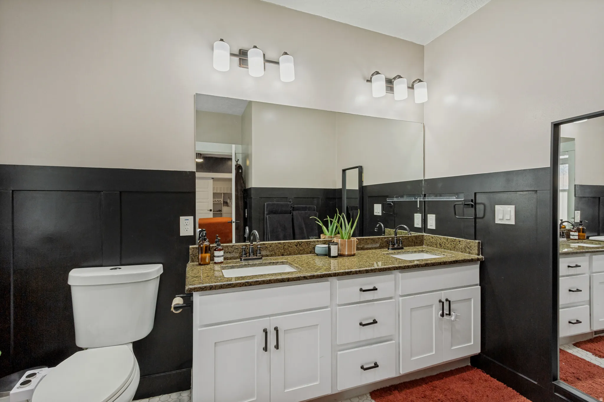 Dual vanity with white shaker-style cabinetry, dark hardware, and a speckled countertop