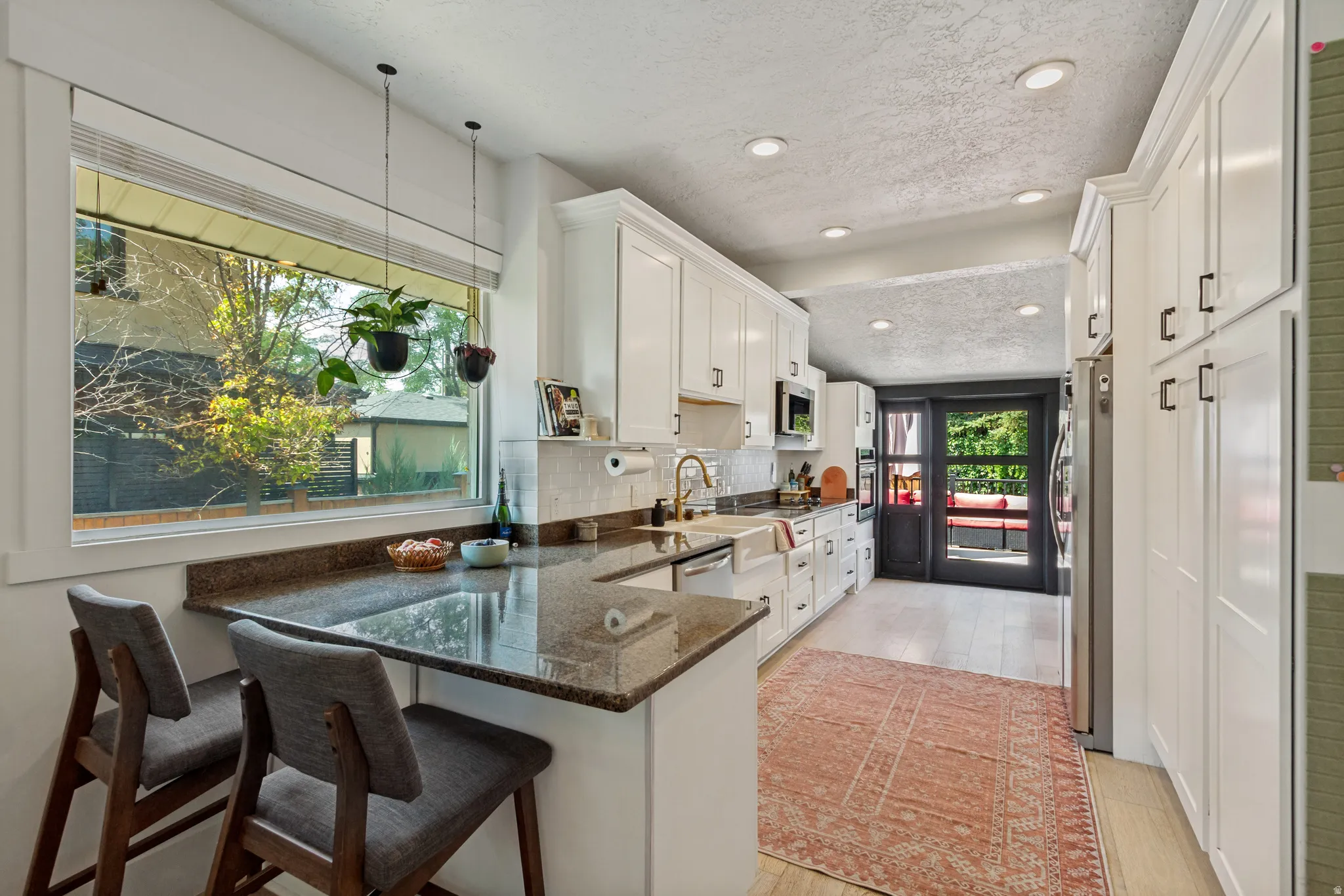 Kitchen featuring a built-in breakfast bar, granite countertops, white cabinetry, recessed lighting, and wood-finish flooring
