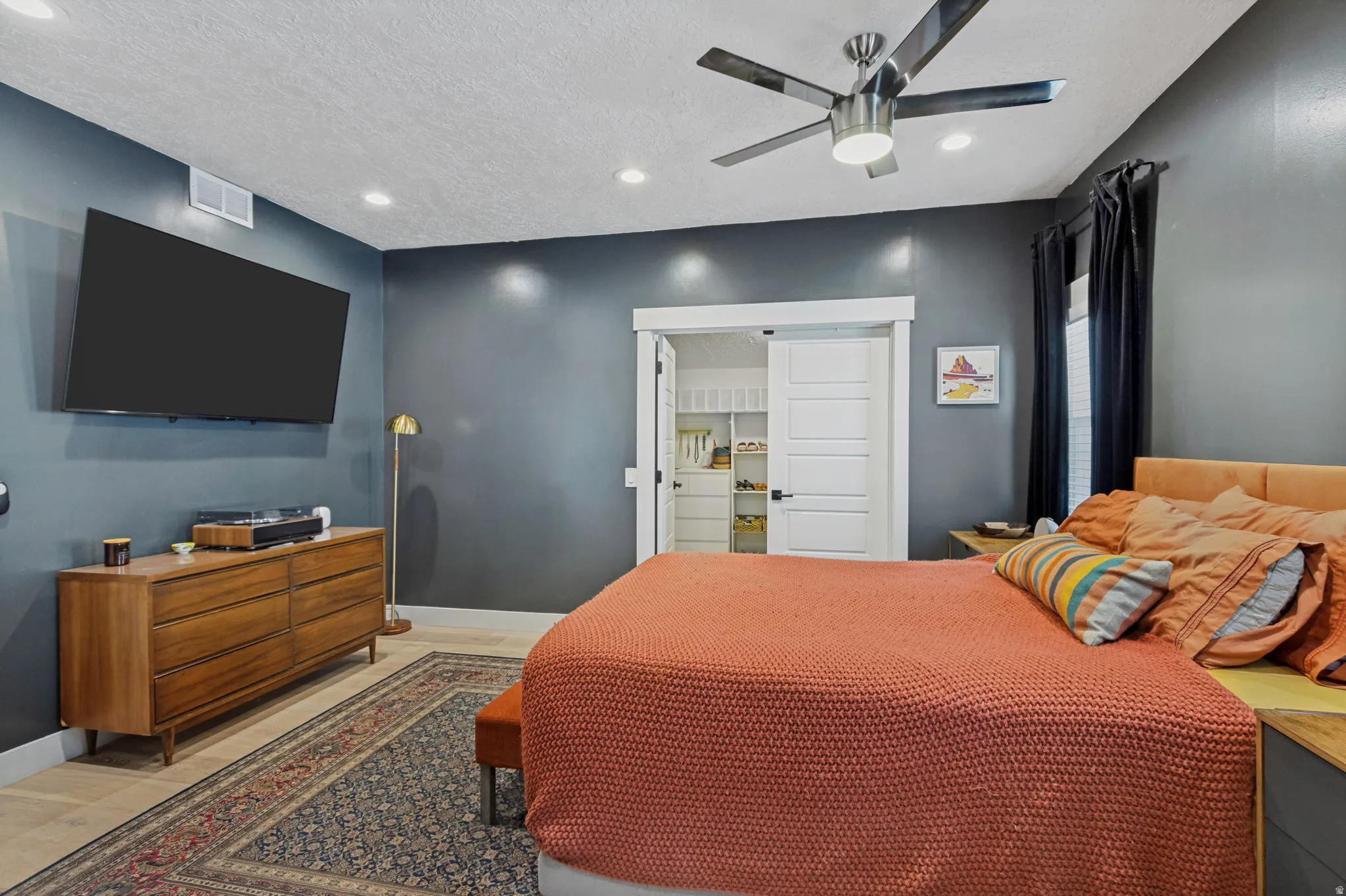 Recessed lighting, ceiling fan with brushed metal finish, wood-finish flooring, white trim, and sliding barn doors revealing built-in closet shelving