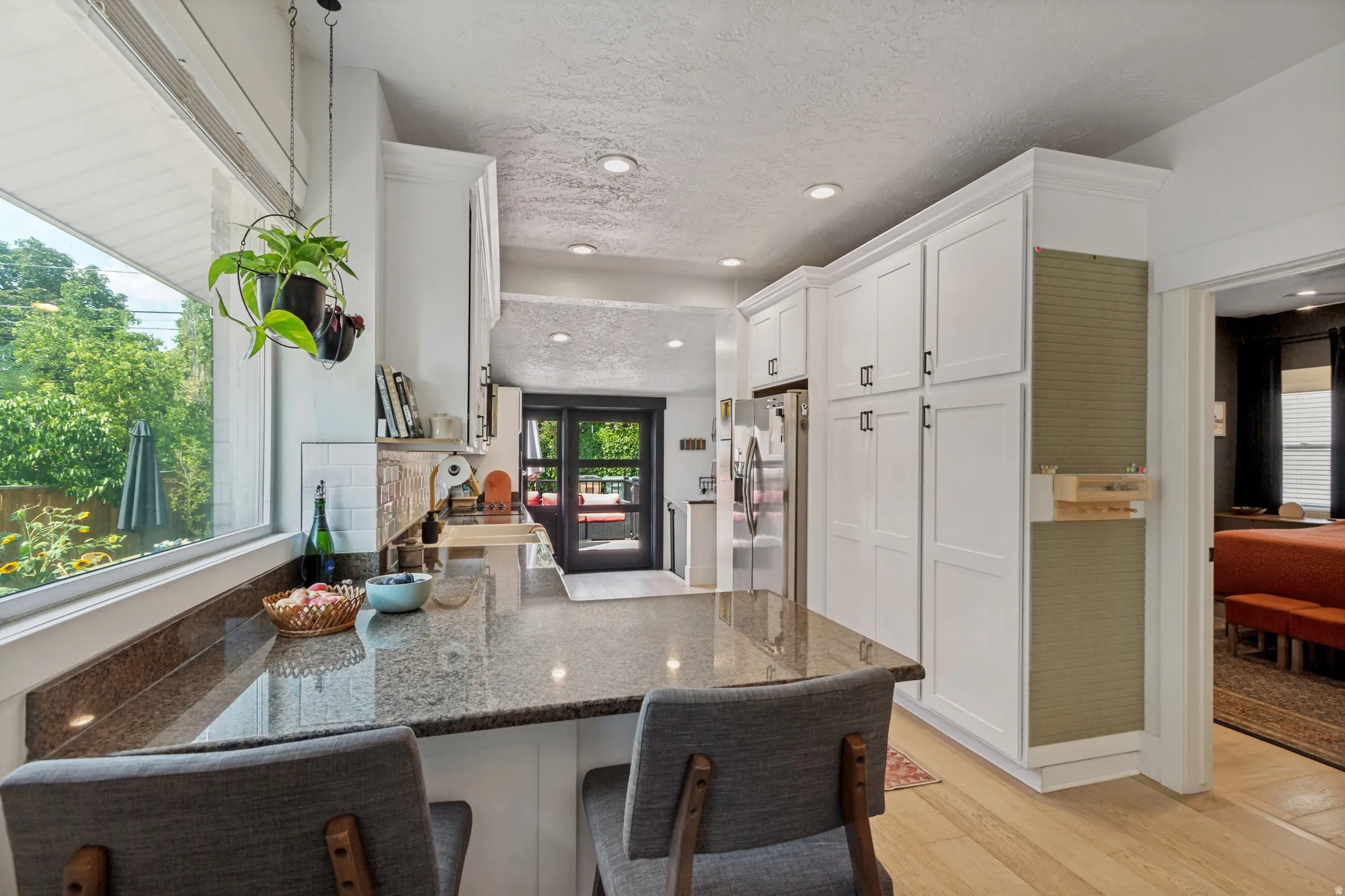 Kitchen featuring white shaker cabinetry, recessed lighting, wood-finish flooring, a granite countertop, and a window overlooking exterior greenery