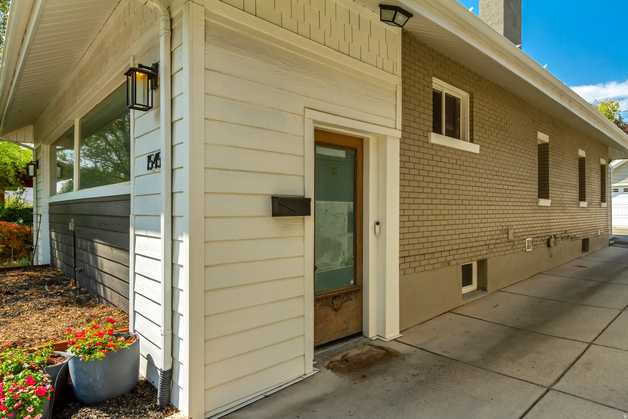 Exterior featuring light-colored horizontal siding, a two-tone brick facade, and multiple windows