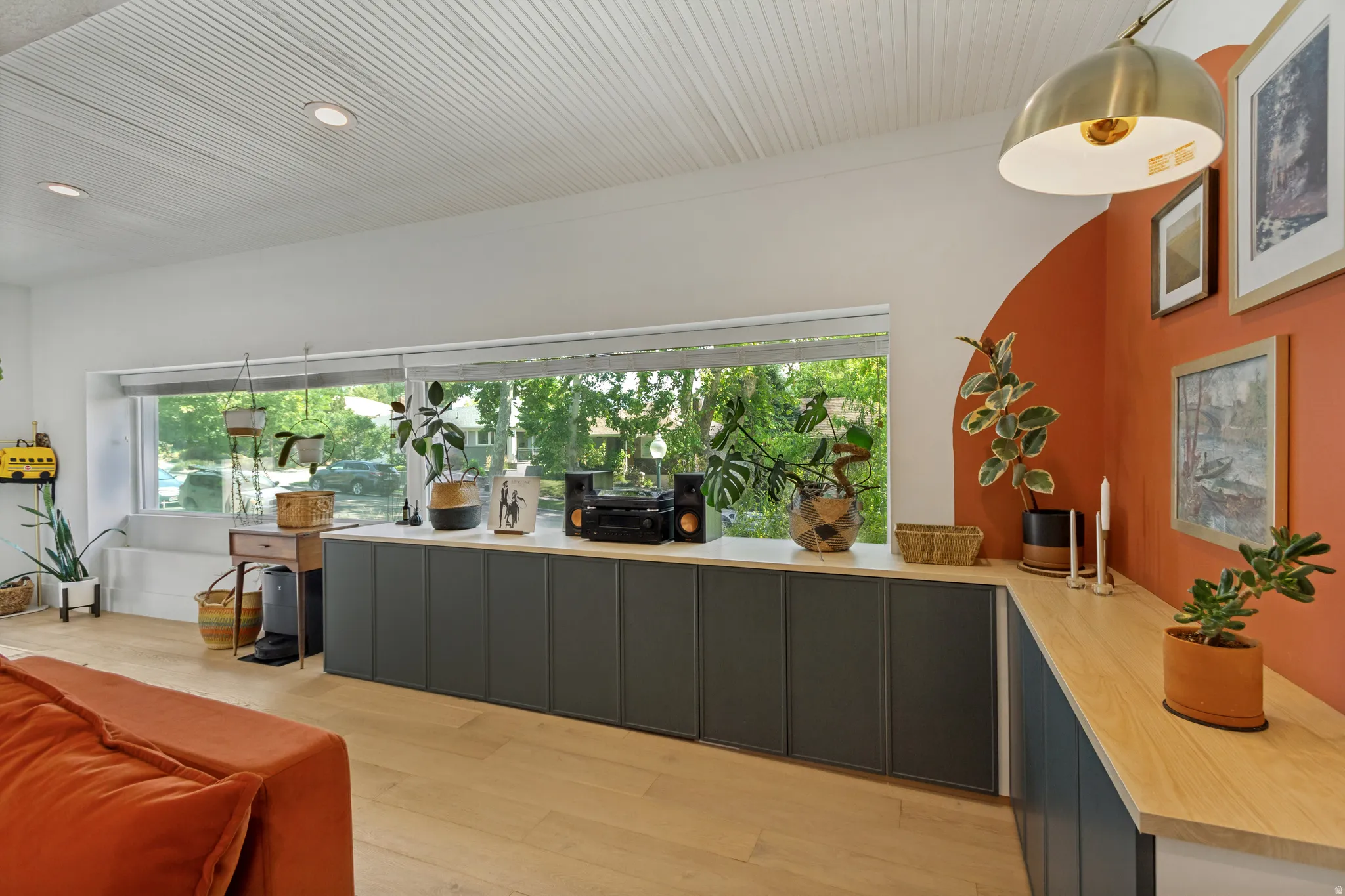 Wood-finish flooring, built-in lower cabinetry with light wood-finish countertops, expansive horizontal window, paneled ceiling, and recessed lighting