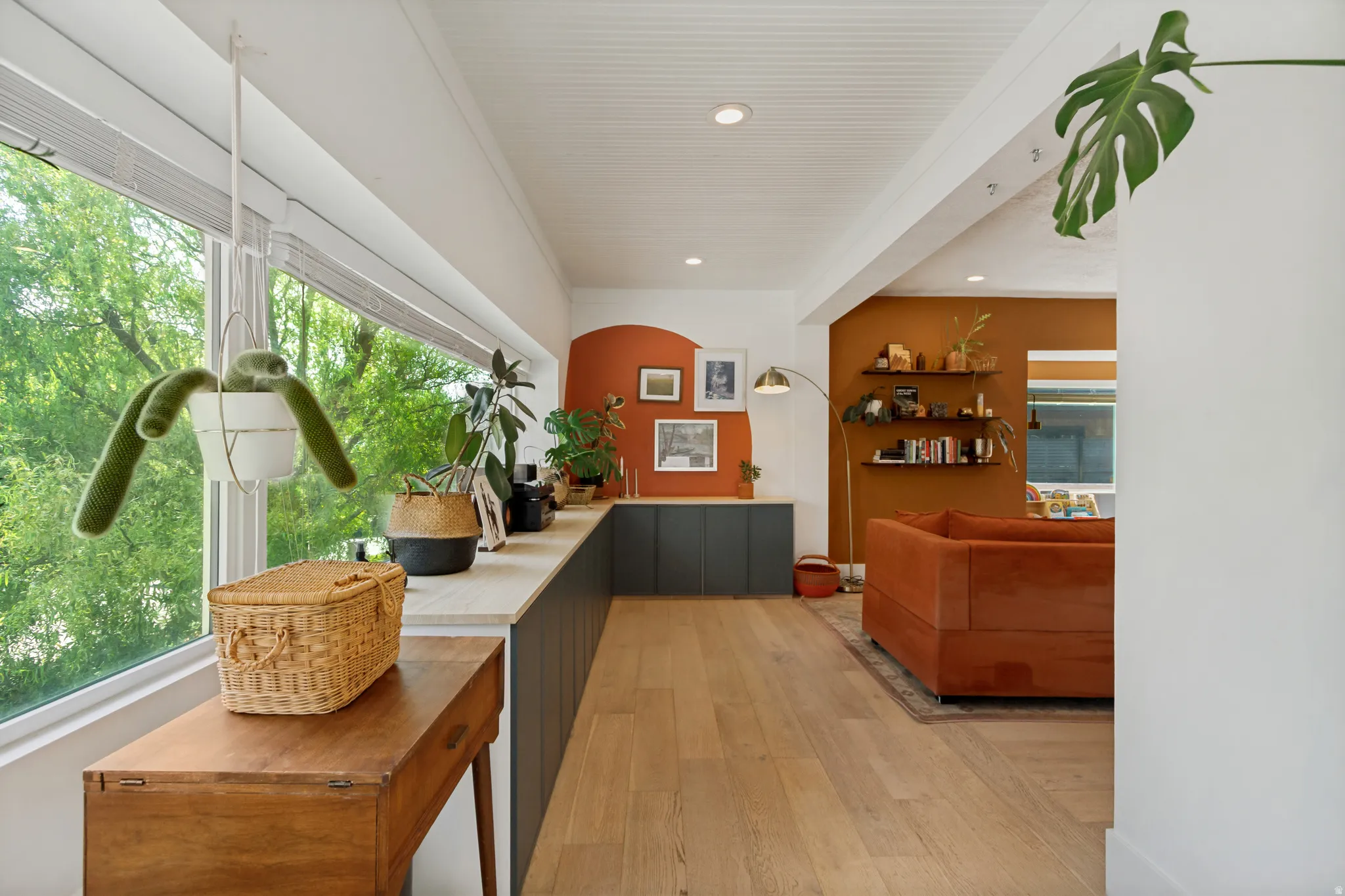 Expansive window wall, wood-finish flooring, built-in shelving, recessed lighting, and a painted accent wall
