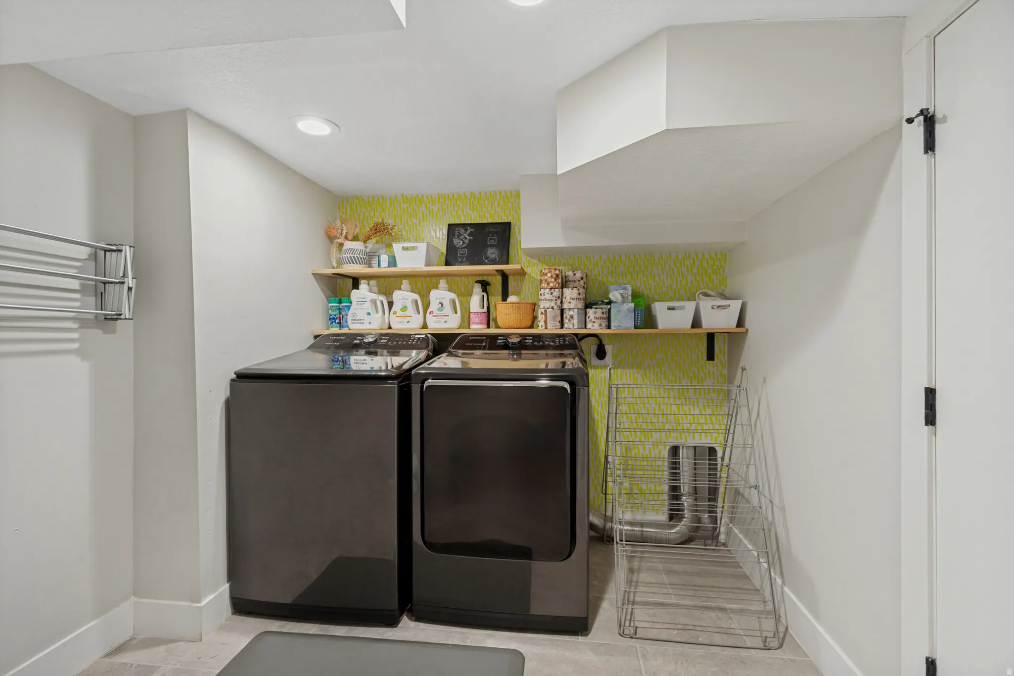 Built-in wooden shelving with wall-mounted brackets, light-toned flooring, and a wall-mounted drying rack