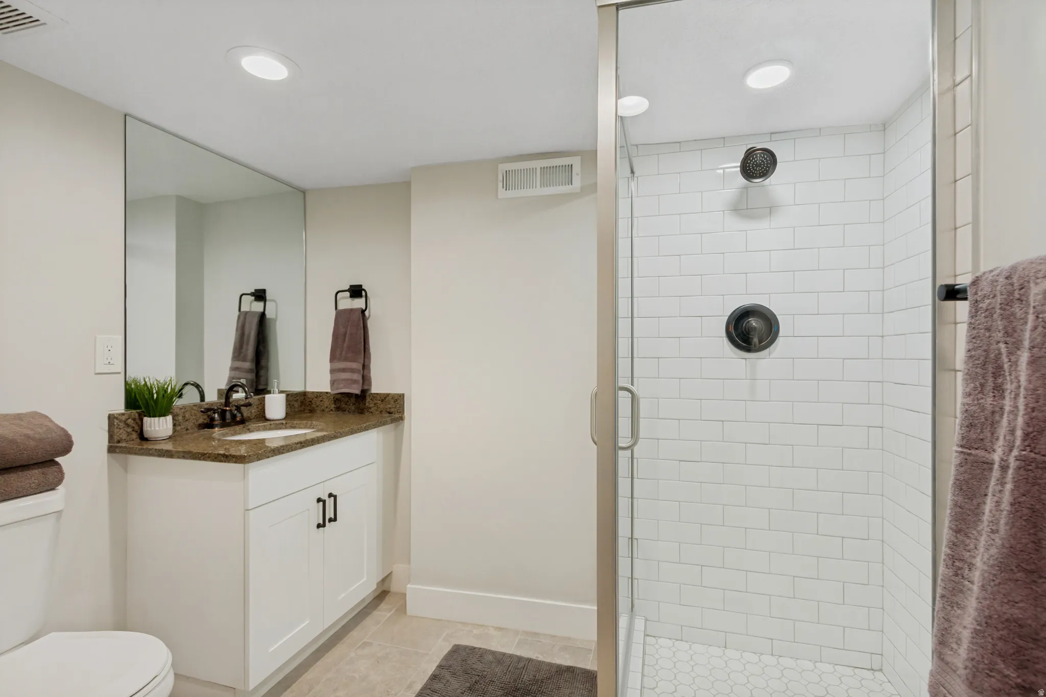 Glass-enclosed shower with subway tile surround and hexagonal floor tiles