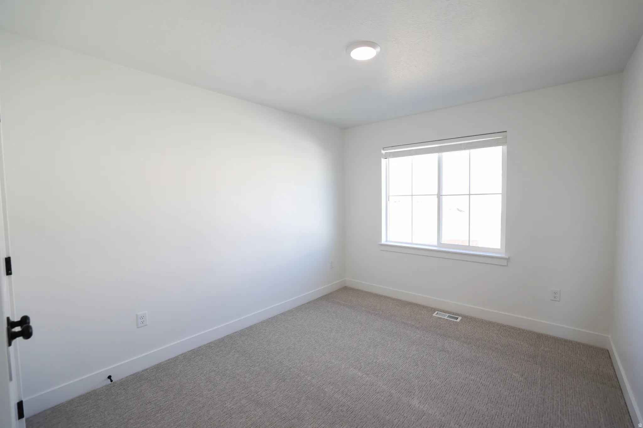 Neutral-toned carpeting, white walls, and a recessed ceiling light fixture