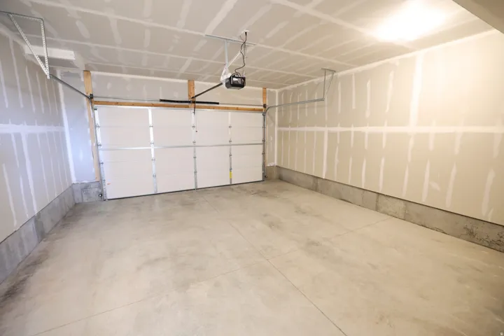Spacious garage featuring a concrete floor, overhead lighting, and an automatic garage door opener