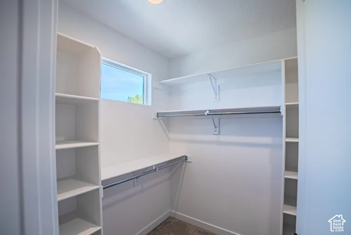 White built-in shelving, chrome hanging rods, recessed lighting, and a horizontal window