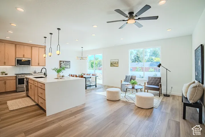 Spacious open-concept living area featuring wood-finish flooring, recessed lighting, and a modern ceiling fan