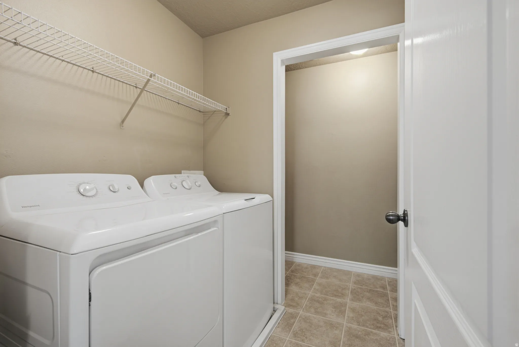 Wire shelving, neutral wall paint, white trim, and tiled flooring