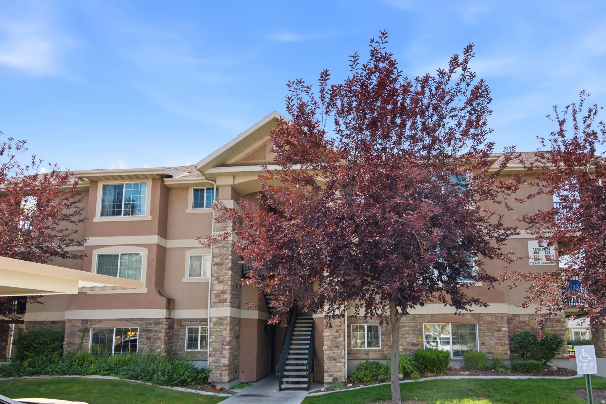Multi-level building exterior featuring stucco siding and stone veneer accents