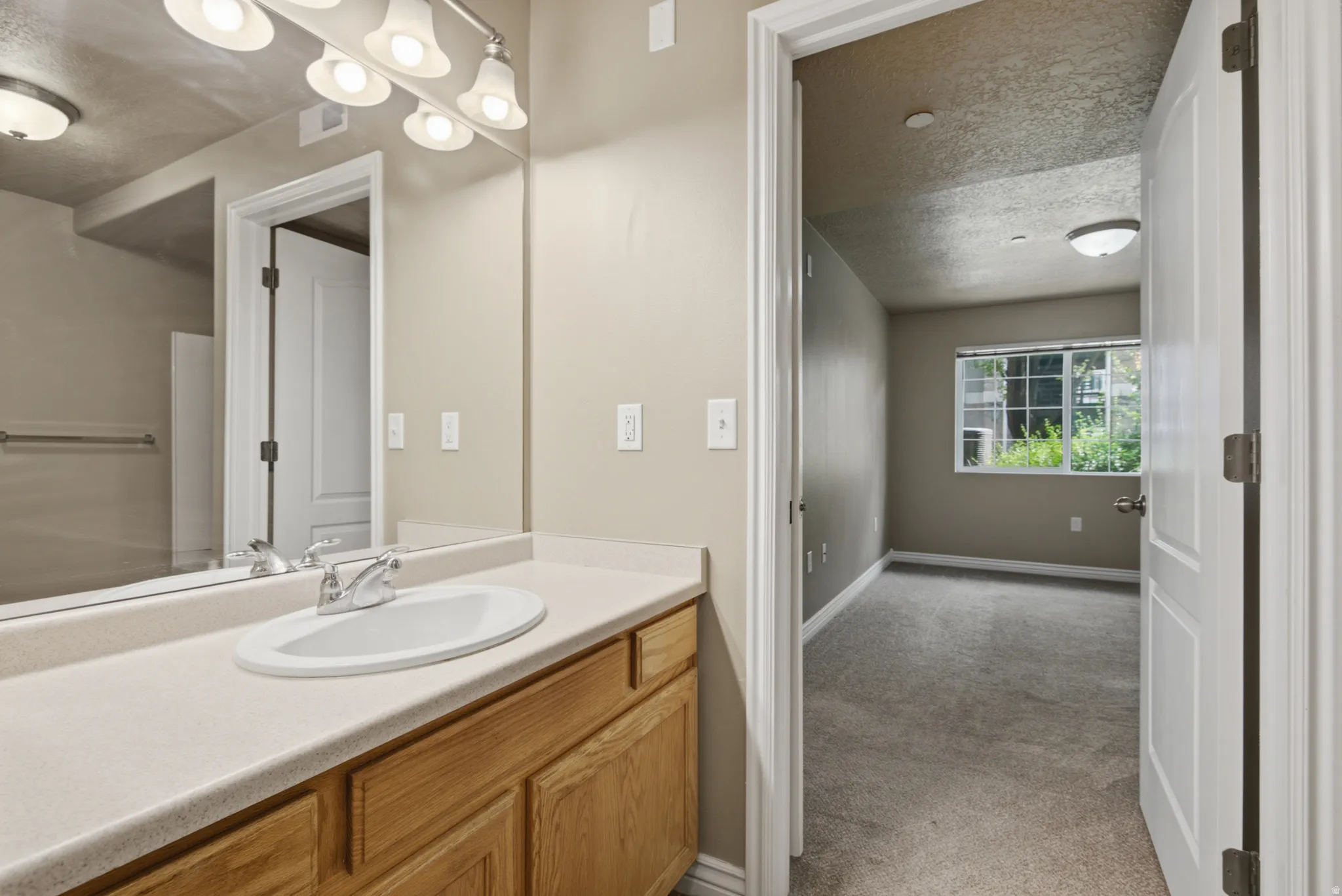 Bathroom vanity with a single basin sink, chrome faucet, and light wood-finish cabinetry