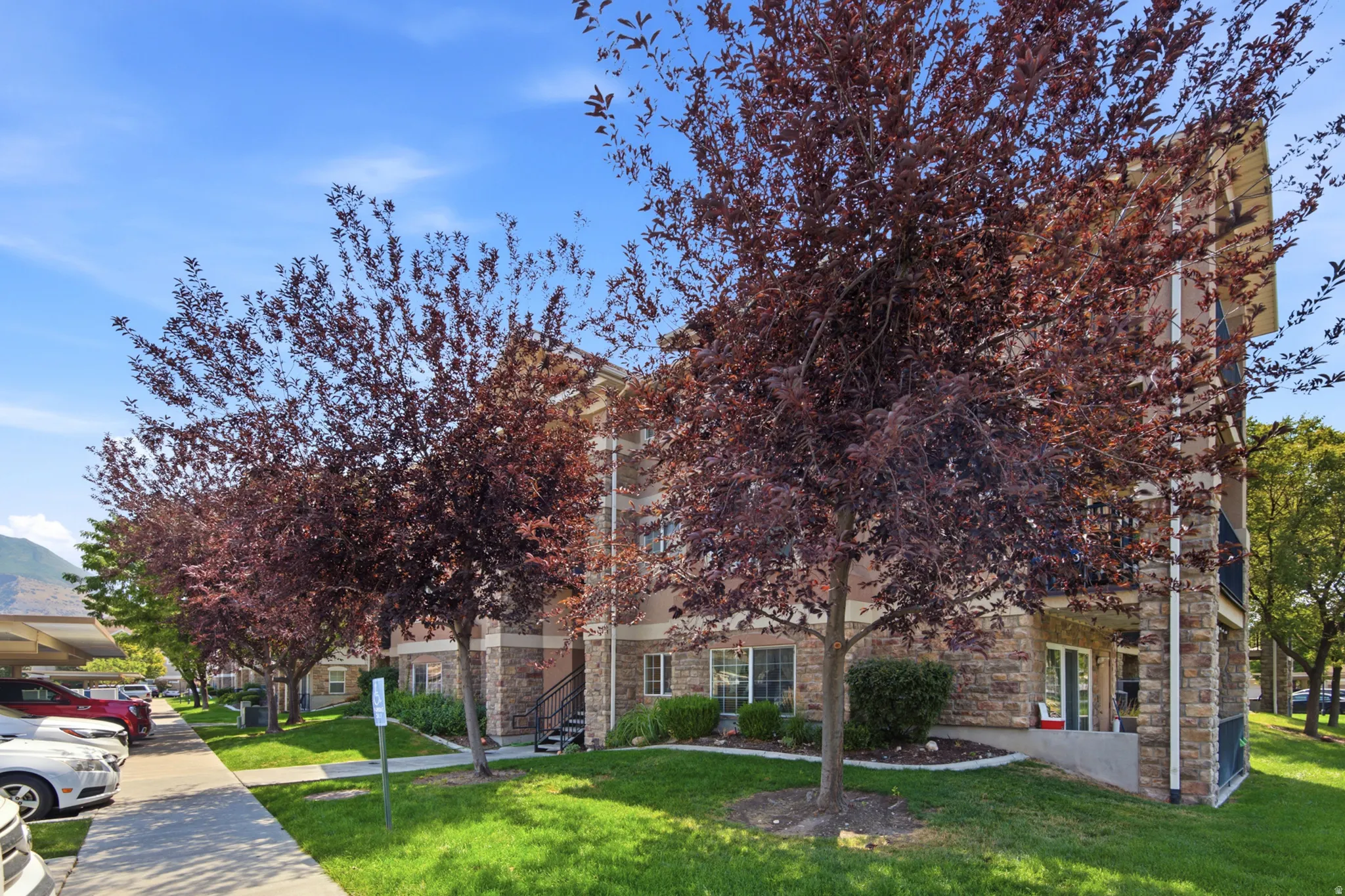 Stone veneer facade with multiple residential units, featuring mature trees and landscaped grounds