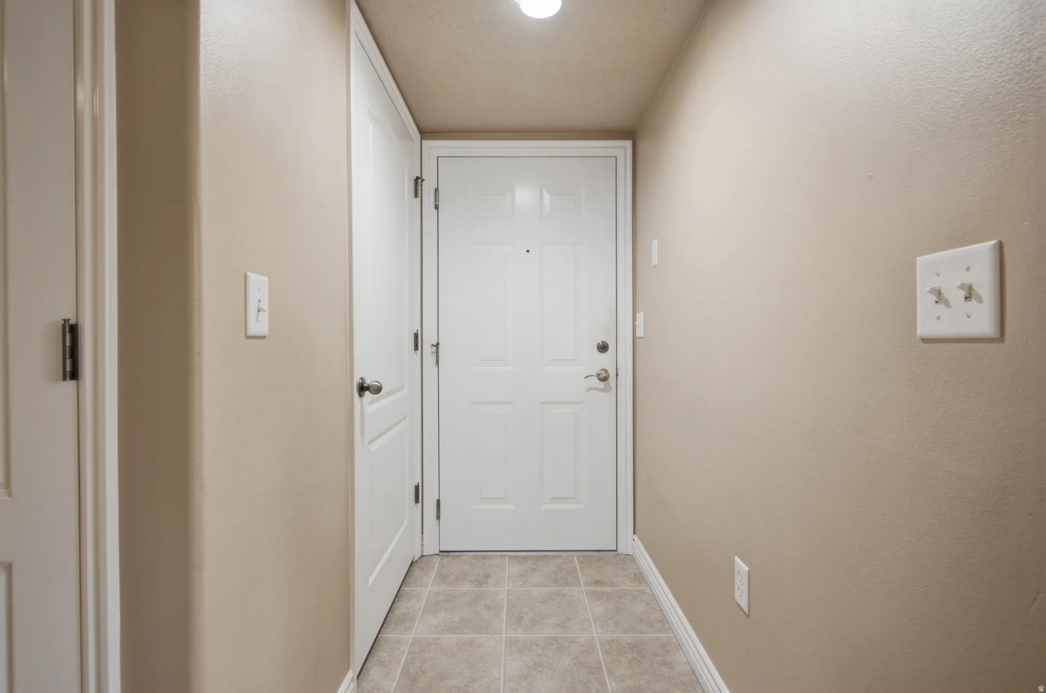 Tiled entryway with neutral wall color and white panel doors