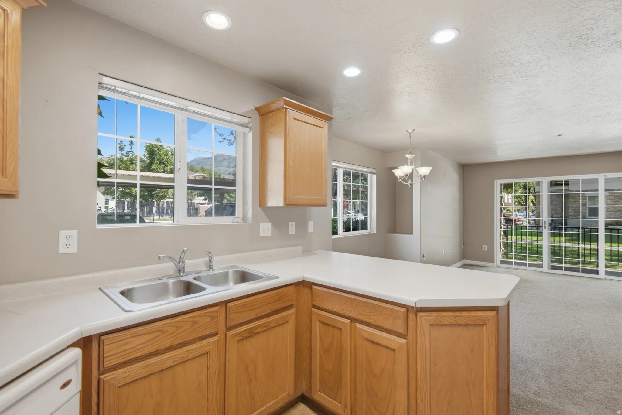 Kitchen featuring wood cabinetry, a dual basin stainless steel sink, and white countertops